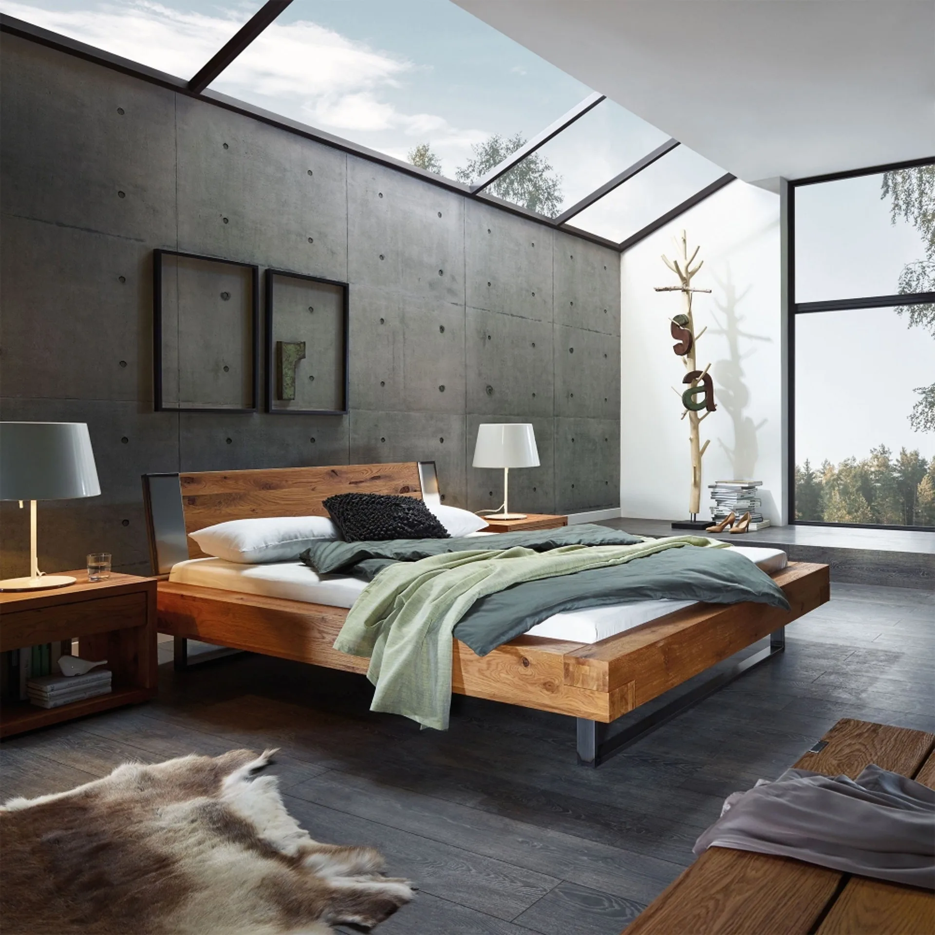 Schlafzimmer unter einem Dach mit schrägen Fenstern, massivem Holzbett und grauer Betonwand.